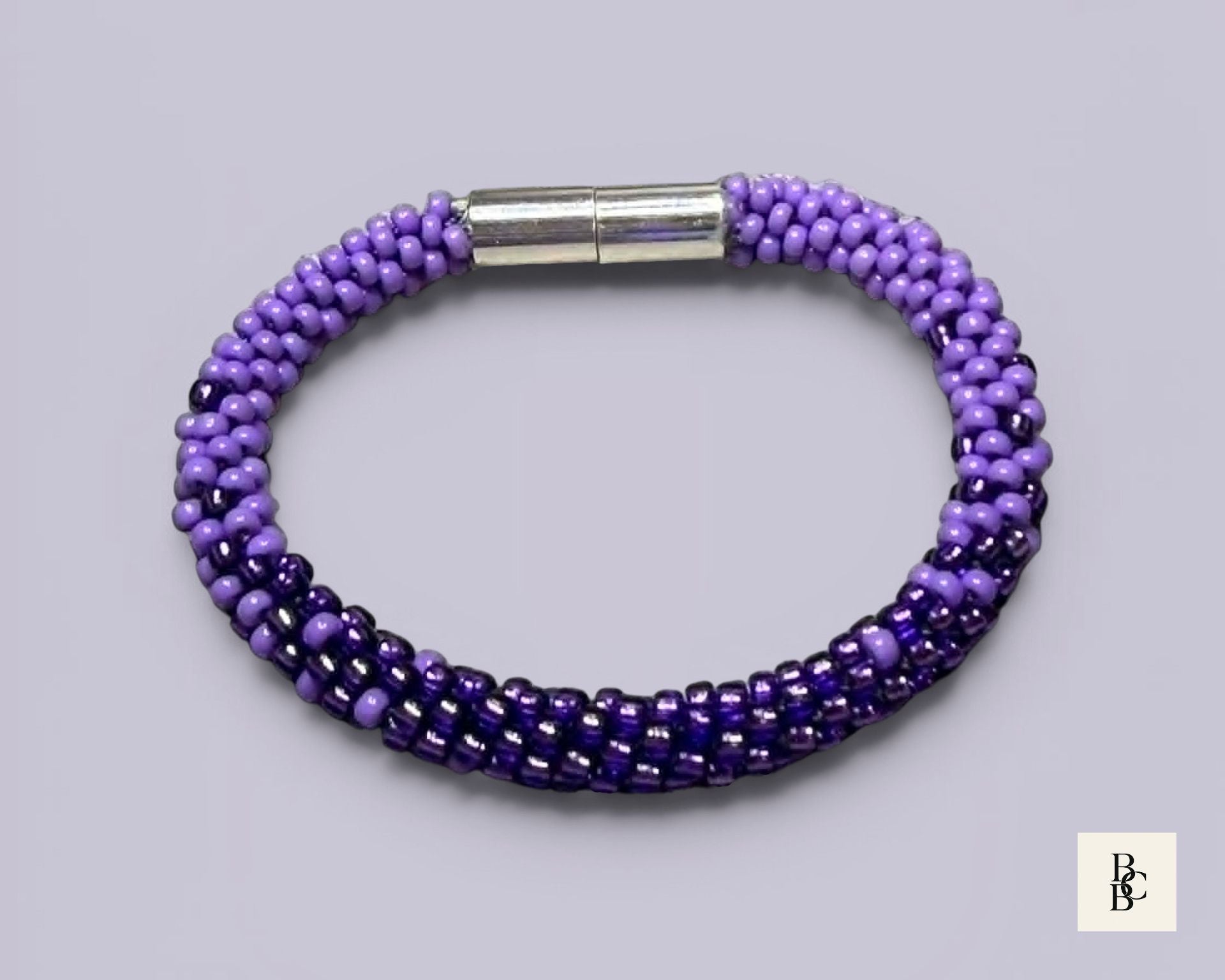 Shades of Violet handmade Alzheimer’s Awareness Kumihimo bracelet with purple glass seed beads and a silver-tone magnetic clasp.