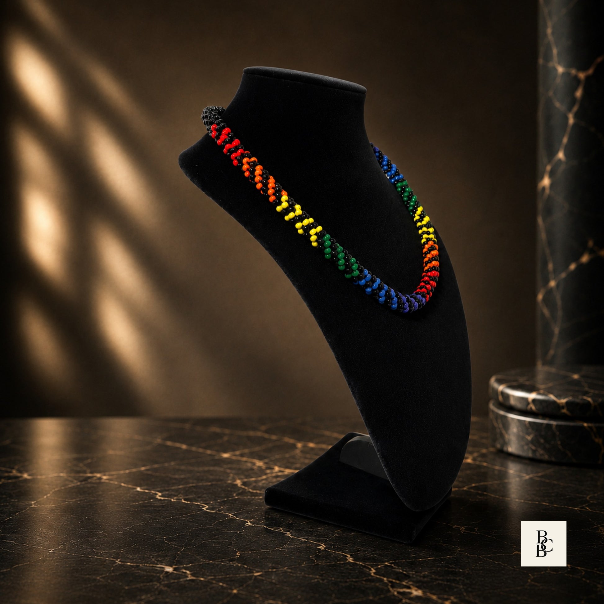 Rainbow Illusion Pride Kumihimo necklace side angle on black velvet bust, showing rainbow glass bead pattern and black accents