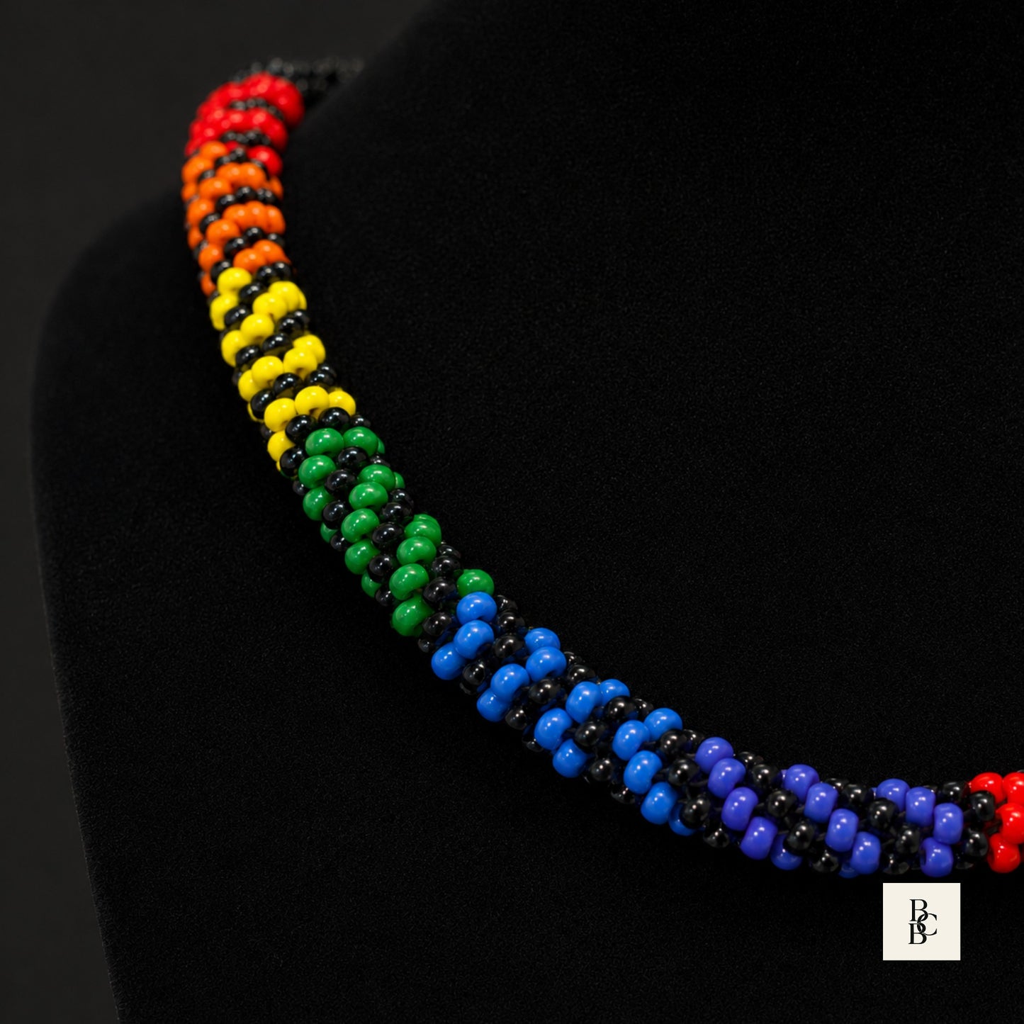 Close-up of Rainbow Illusion Pride Kumihimo necklace, showing handmade rainbow glass seed beads with glossy black accents