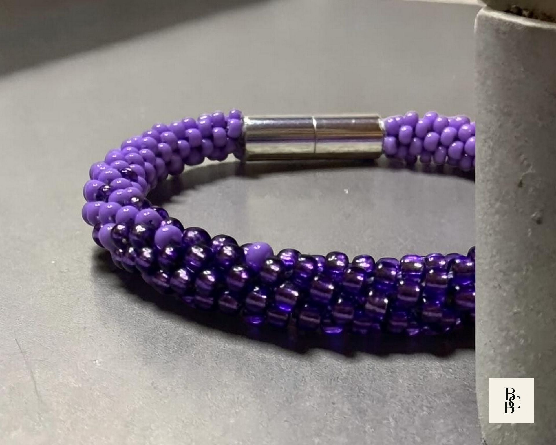 Close-up of the Shades of Violet Alzheimer’s Awareness Kumihimo bracelet, highlighting the purple glass seed bead pattern and silver-tone magnetic clasp.