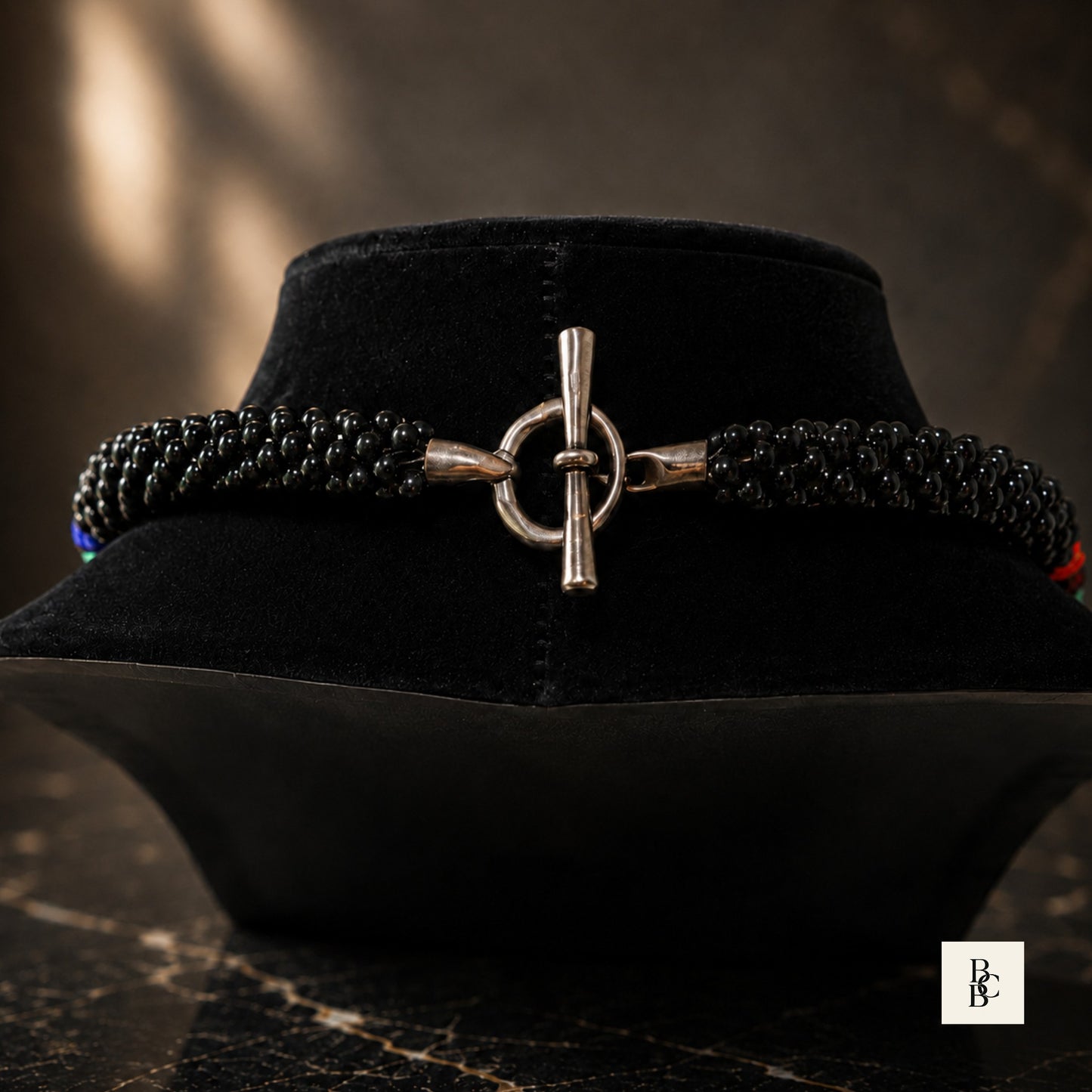 Toggle clasp close-up on Rainbow Illusion Kumihimo necklace, showing silver-tone closure and black beaded braid ends
